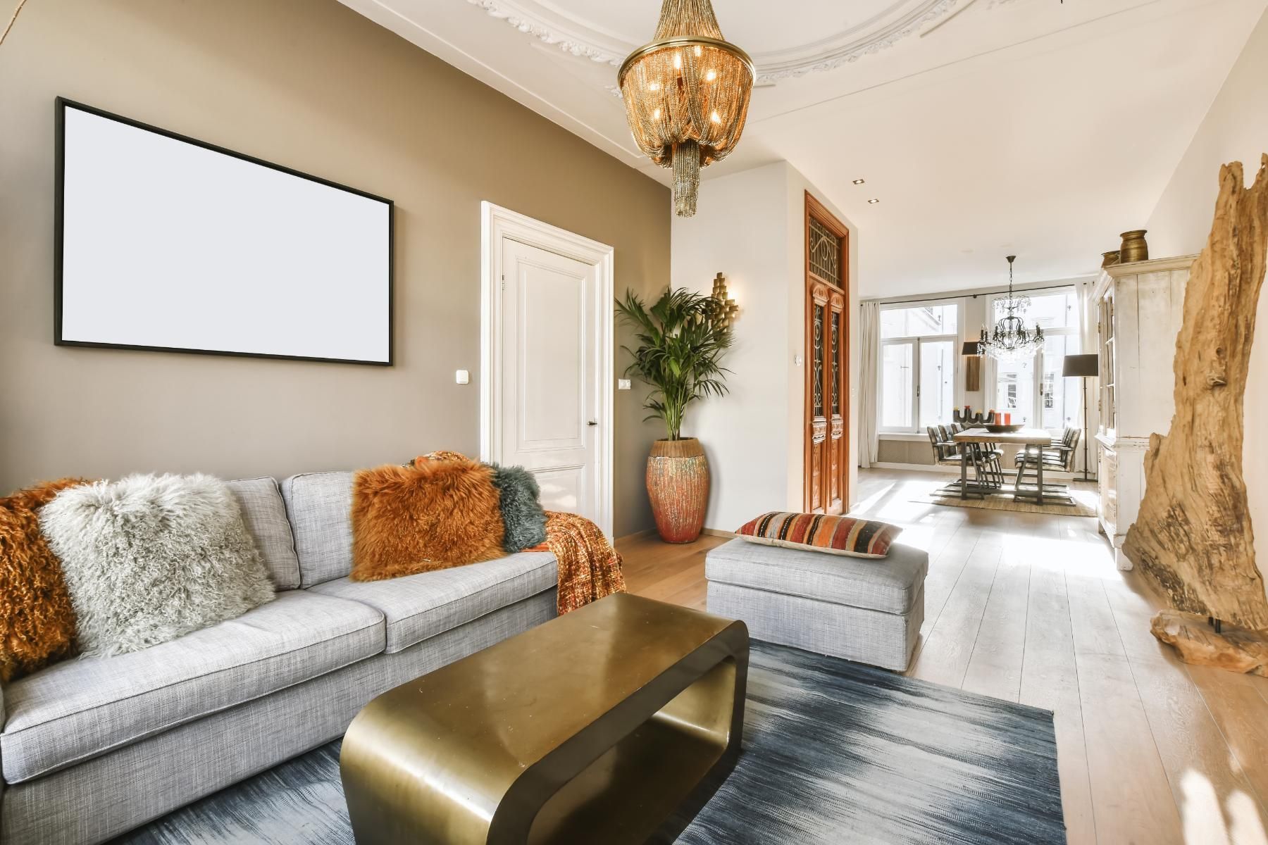 Living room with gray sofa, gold coffee table, and decorative rug; neutral walls and ornate chandelier.