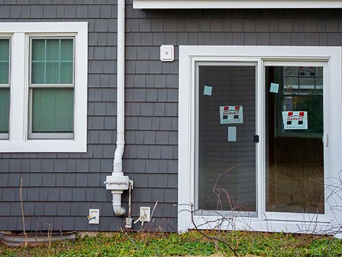 A sliding glass door is being installed on the side of a house.