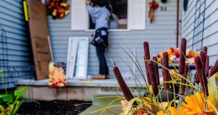 A man is fixing a window on the front of a house.