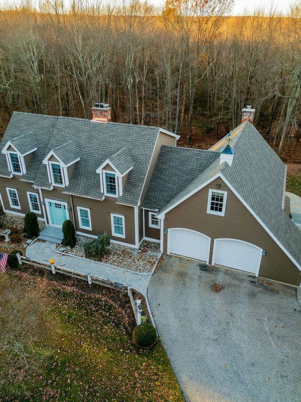 An aerial view of a large house in the middle of a forest.