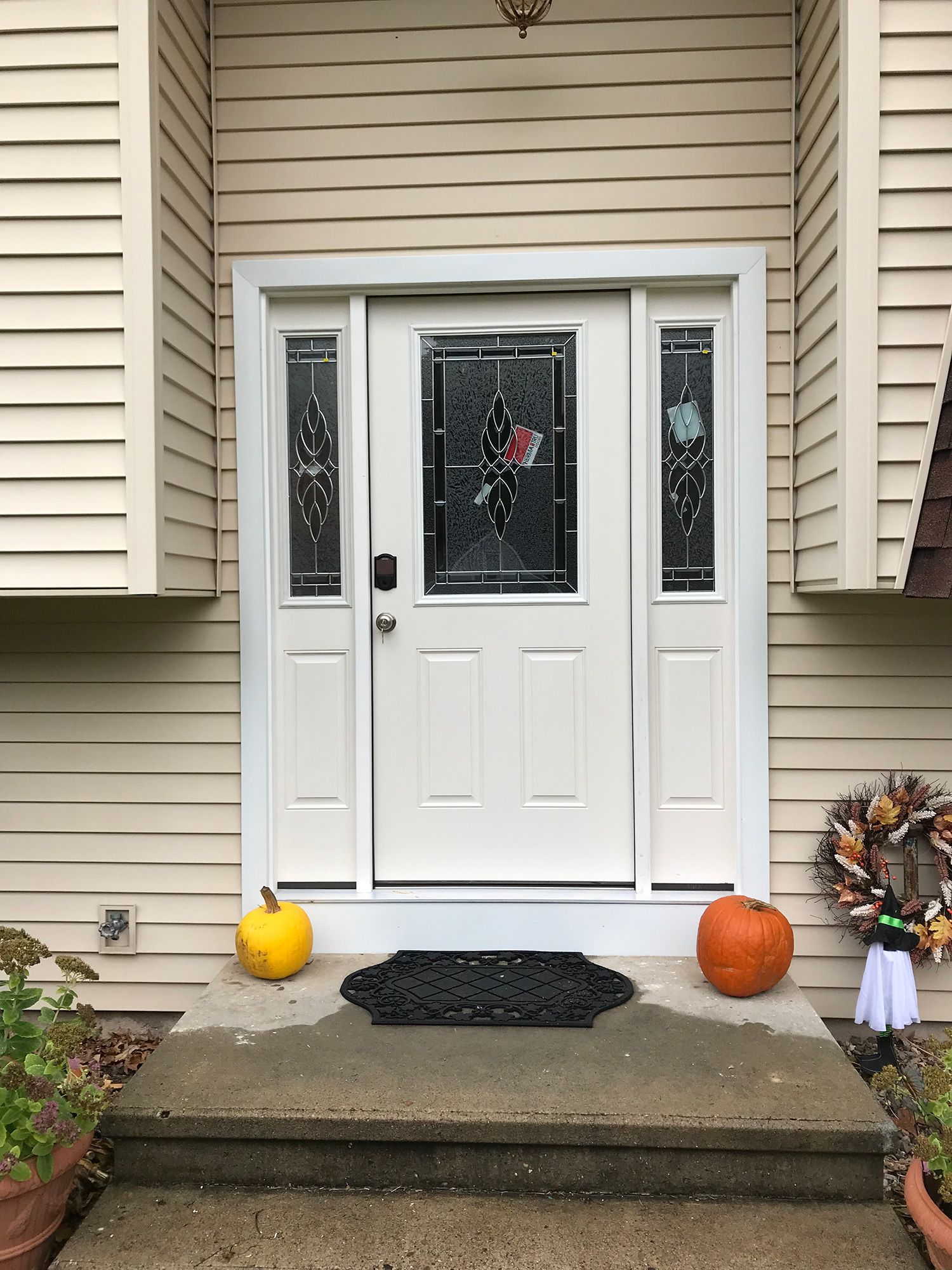 A white front door with pumpkins on the porch of a house.