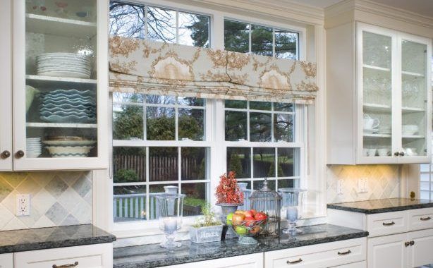 A kitchen with a large window and a bowl of fruit on the counter.