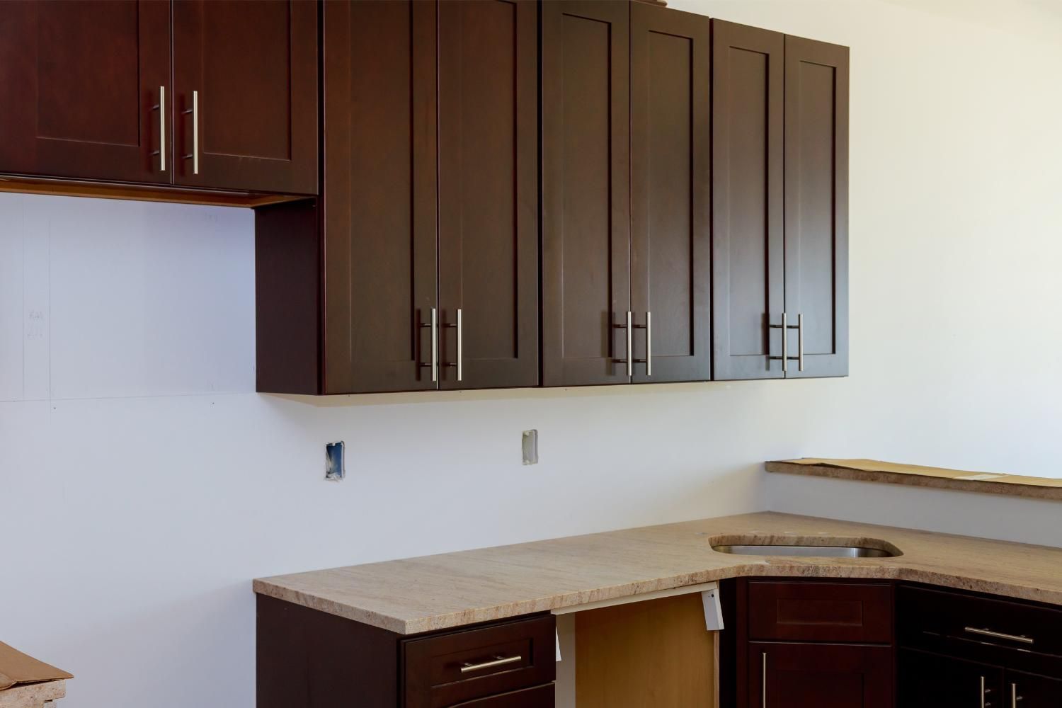 Dark wood kitchen cabinets installed above a beige countertop.