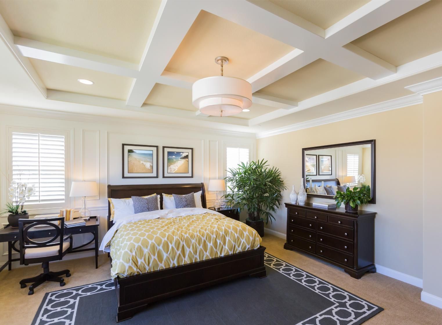 Bedroom with dark furniture, yellow bedspread, coffered ceiling, and rug.