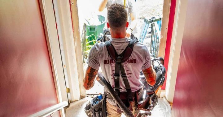 A man is walking down a set of stairs with a vacuum cleaner.