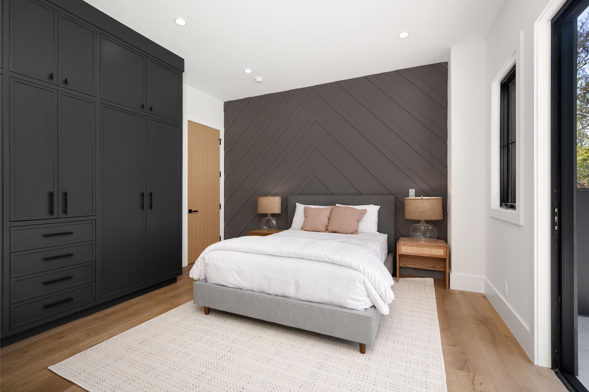 Modern bedroom with a bed, dark accent wall, black wardrobe, and rug.