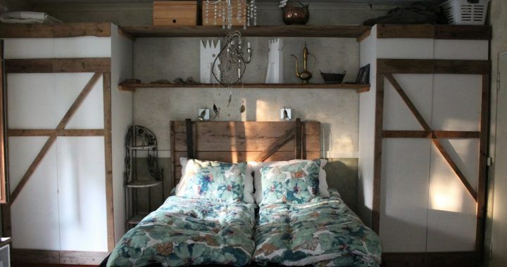 A bedroom with a bed and closets behind it