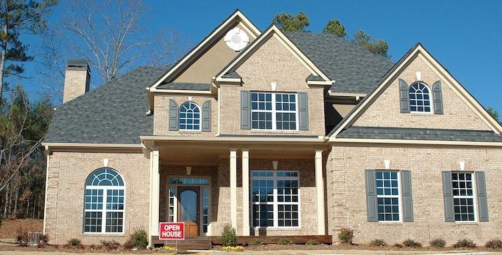 A large brick house with a for sale sign in front of it