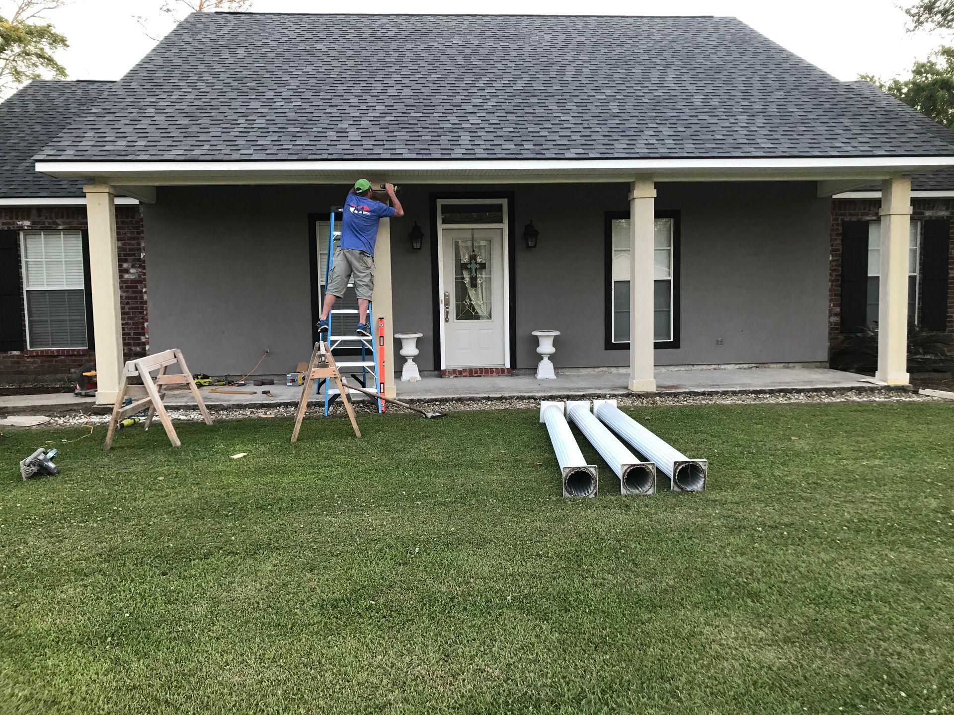 A man is standing on a ladder in front of a house.
