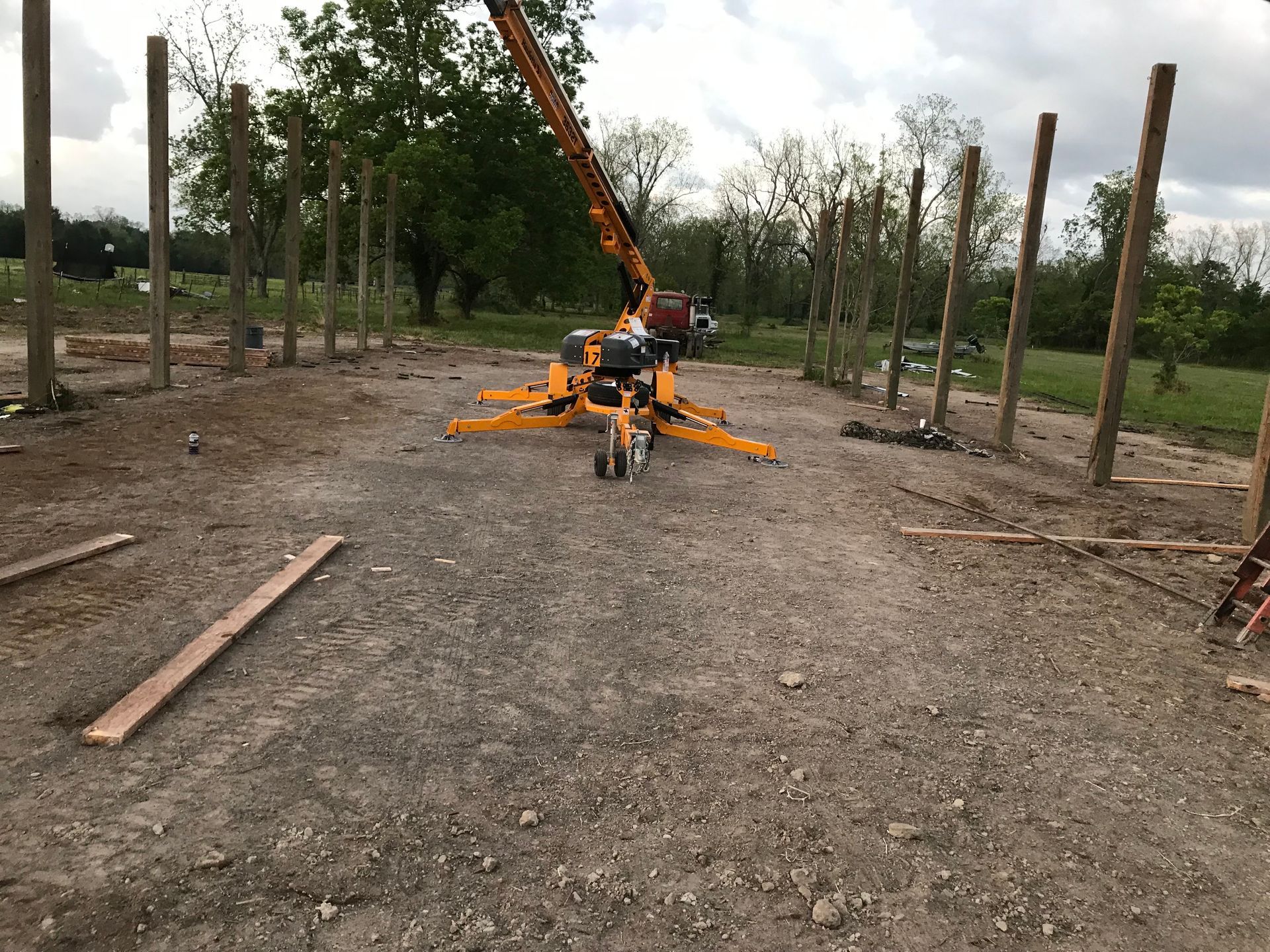 A yellow crane is sitting in the middle of a dirt field.
