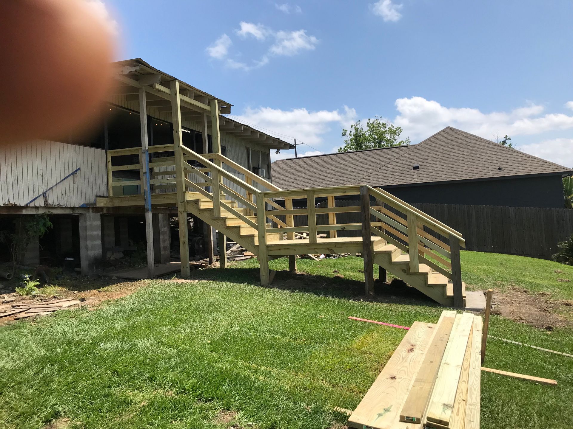 A wooden deck with stairs is being built in the backyard of a house.