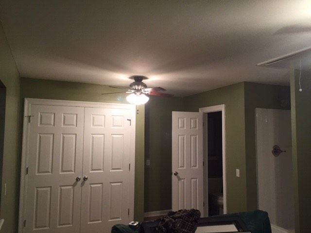 A living room with white doors and a ceiling fan