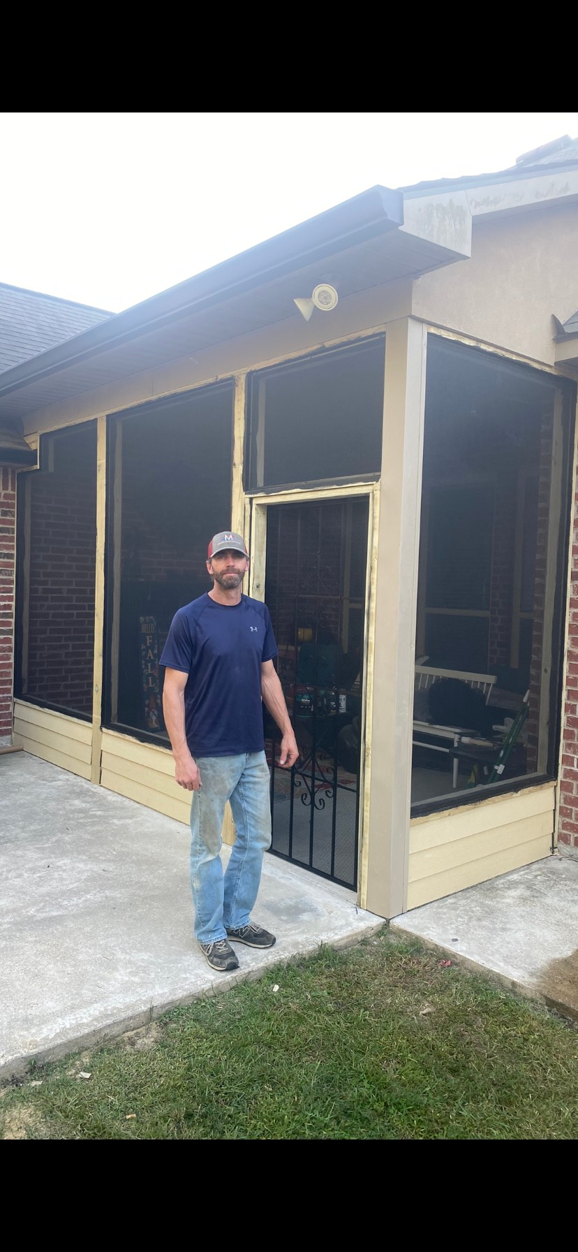 A man is standing in front of a screened in porch.