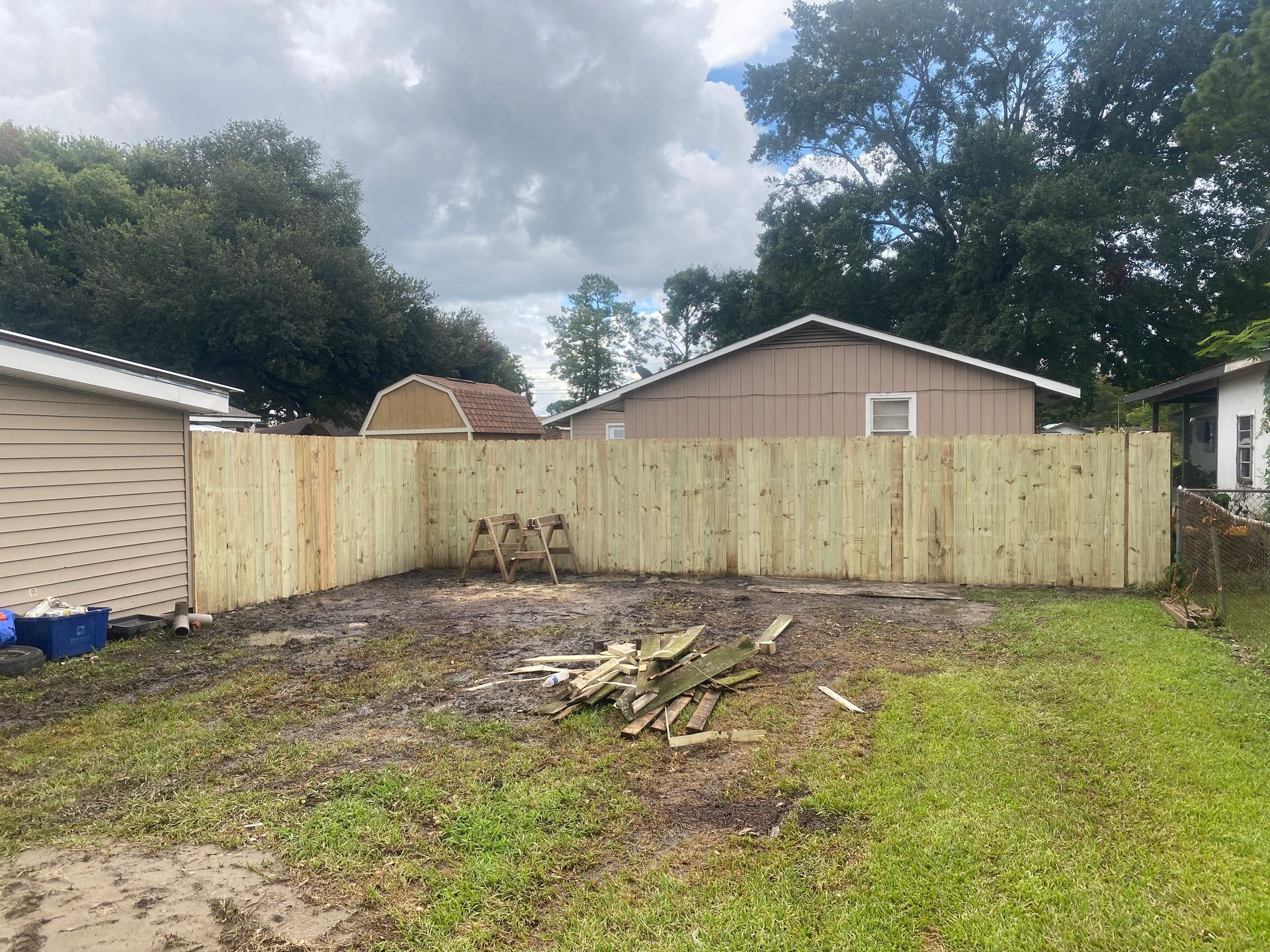 A wooden fence is being built in the backyard of a house.