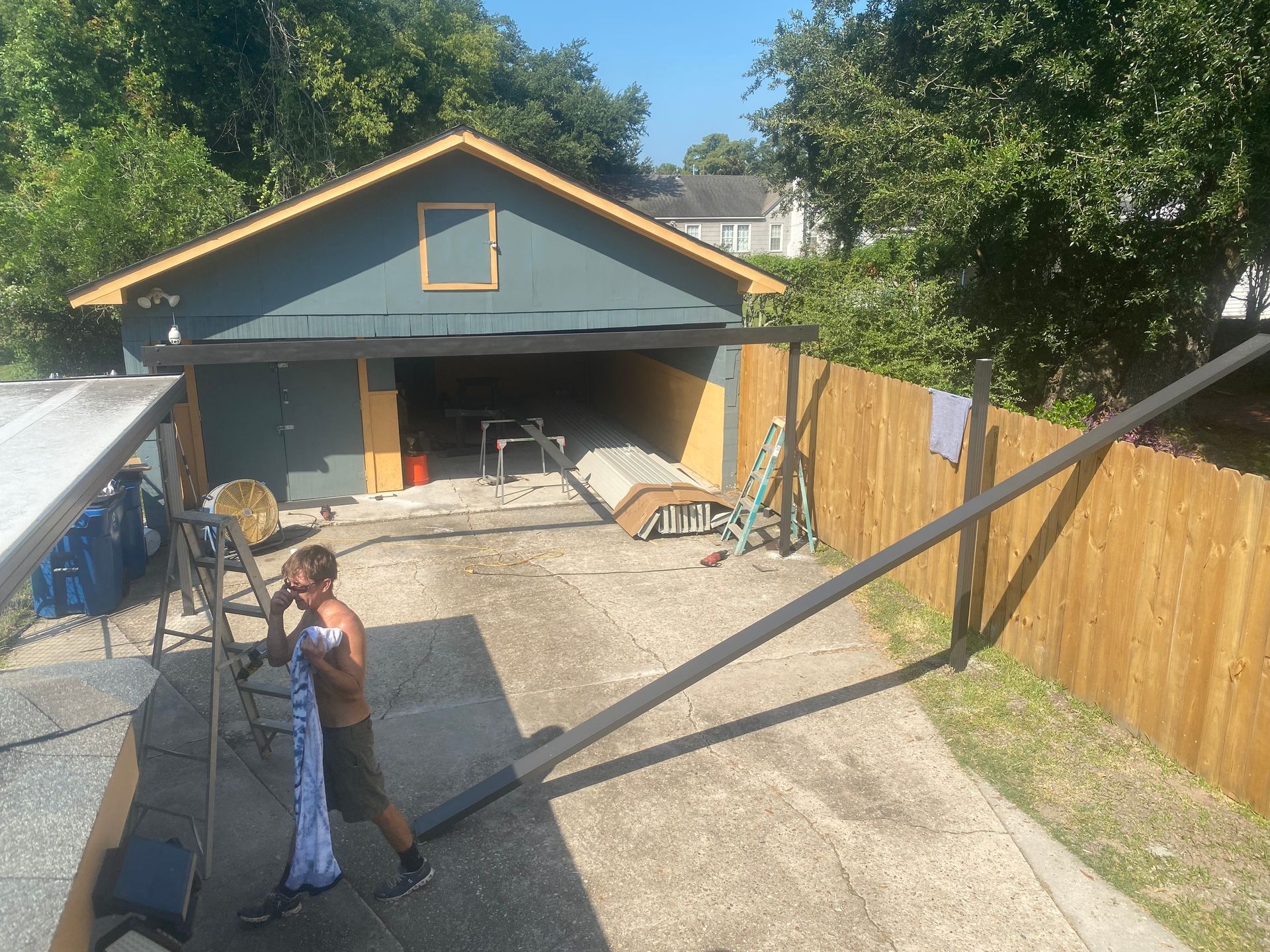 A man is standing in front of a garage holding a pipe