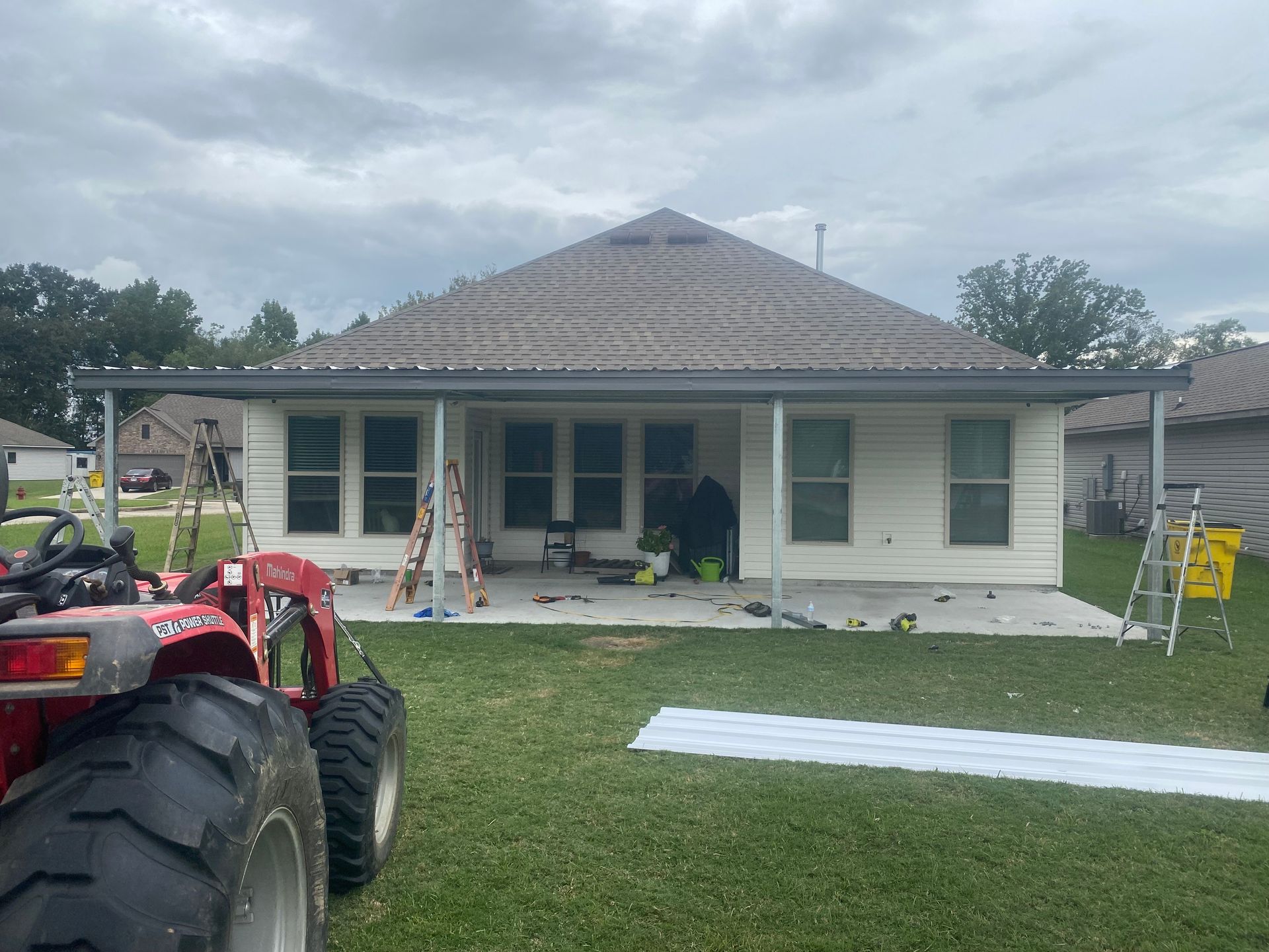 A tractor is parked in front of a house that is being remodeled.