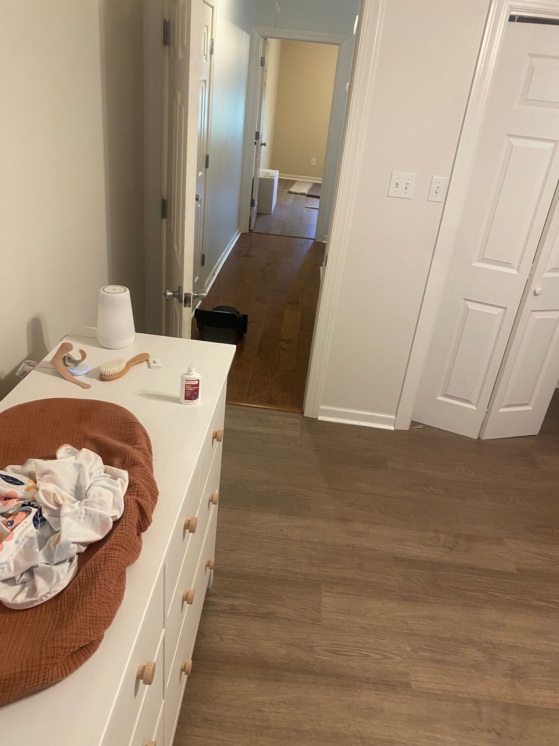 A room with a dresser and a dog bed in it