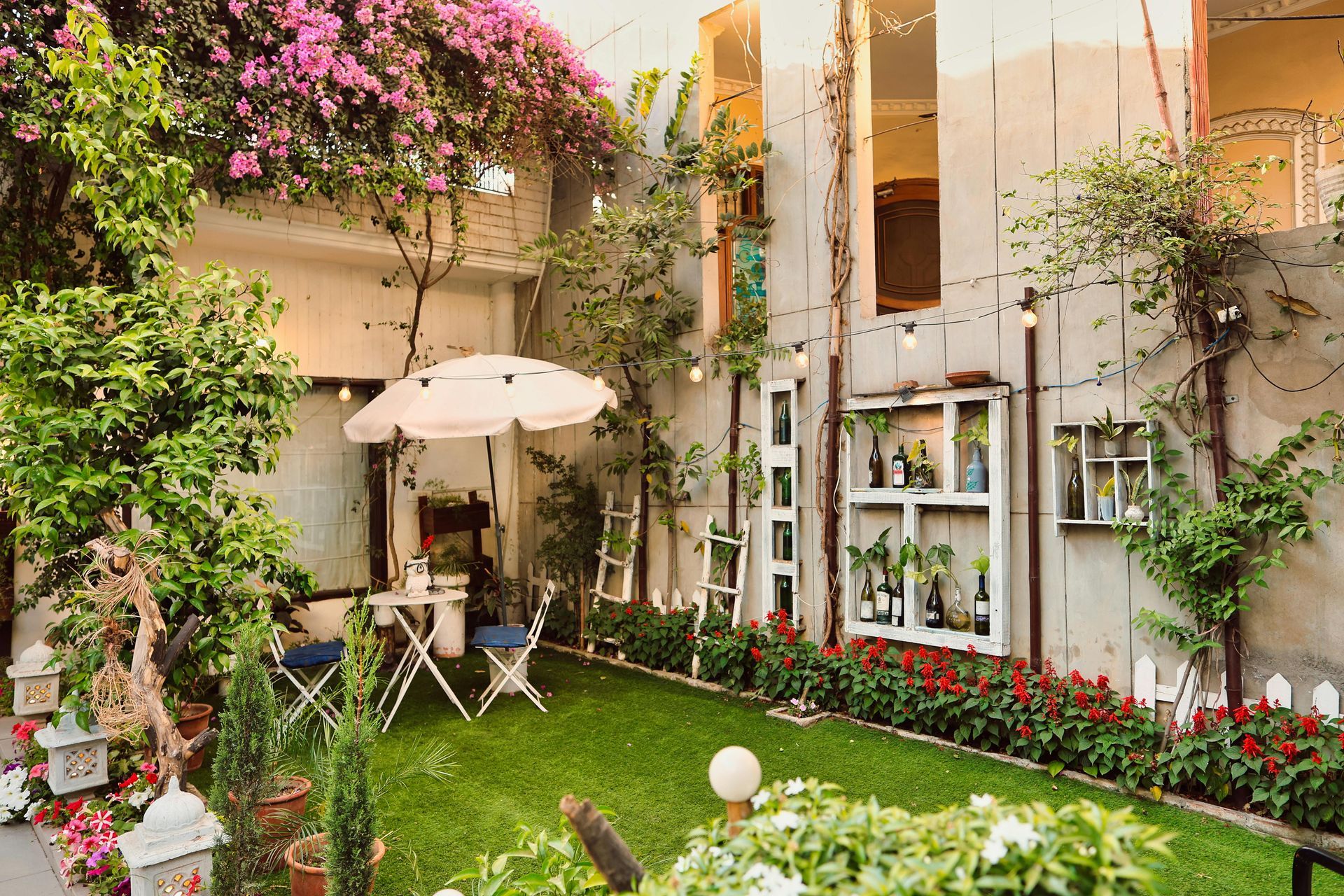 A garden with a table and chairs and an umbrella in front of a building.