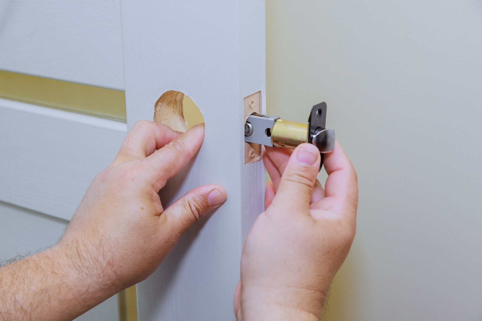 A person is installing a door handle on a white door.