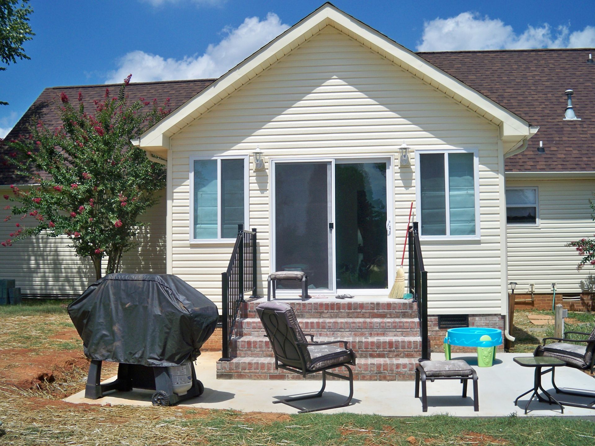 The backyard of a house with a grill and chairs