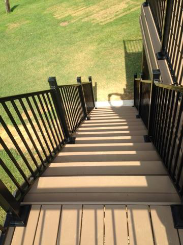 A set of stairs leading up to a deck with a black railing