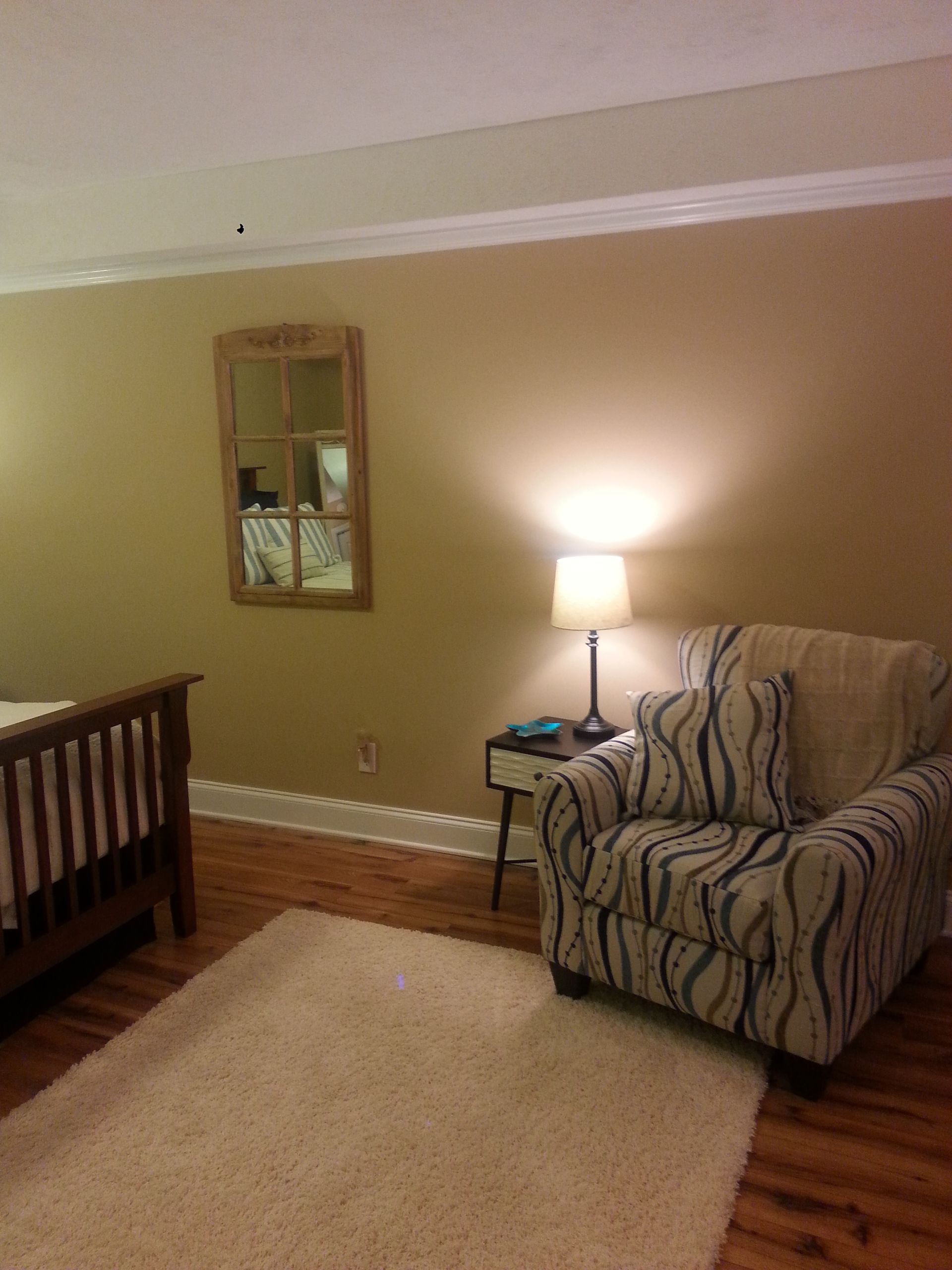 A bedroom with a chair and a mirror on the wall