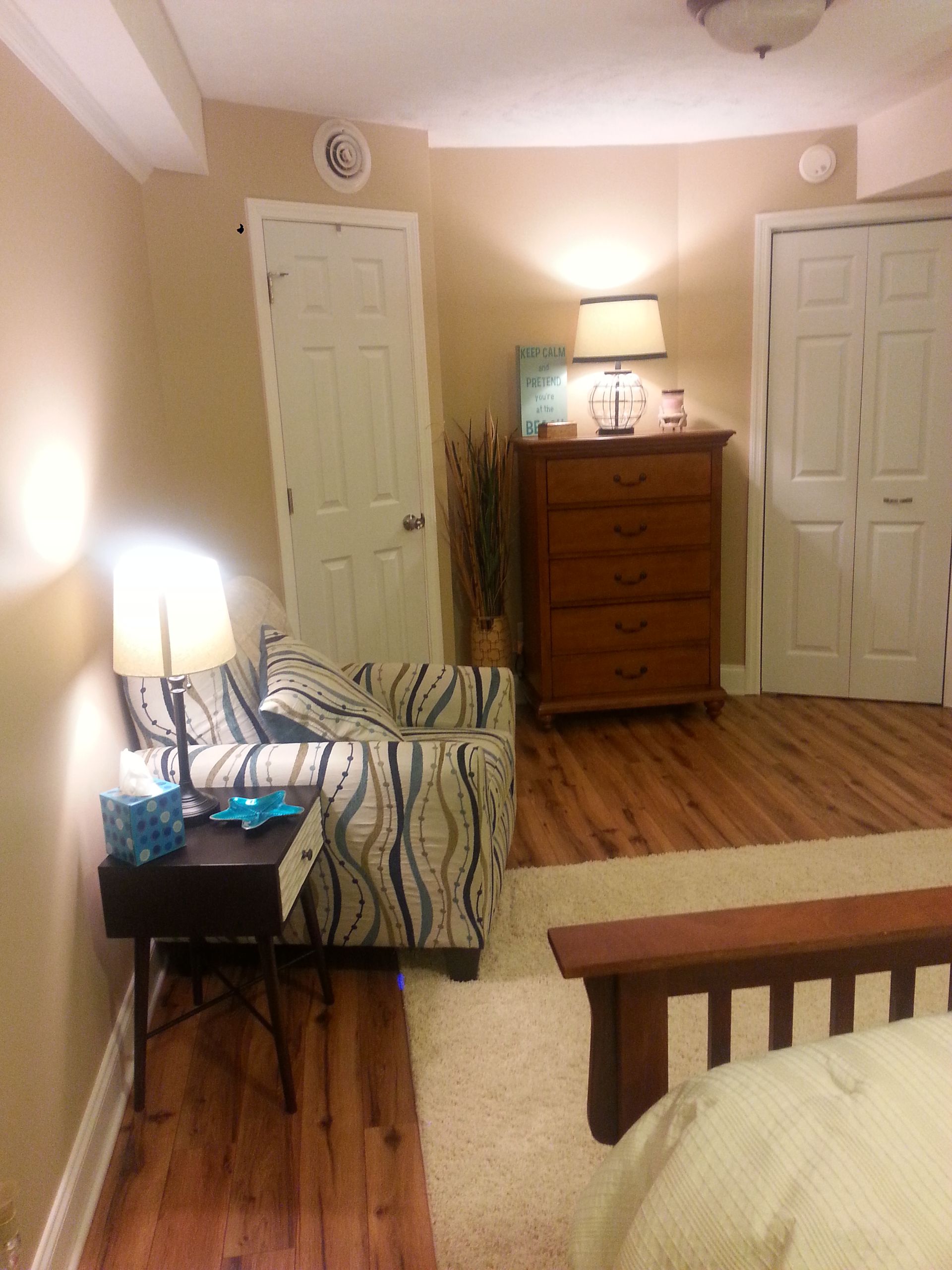 A bedroom with a bed a chair and a dresser