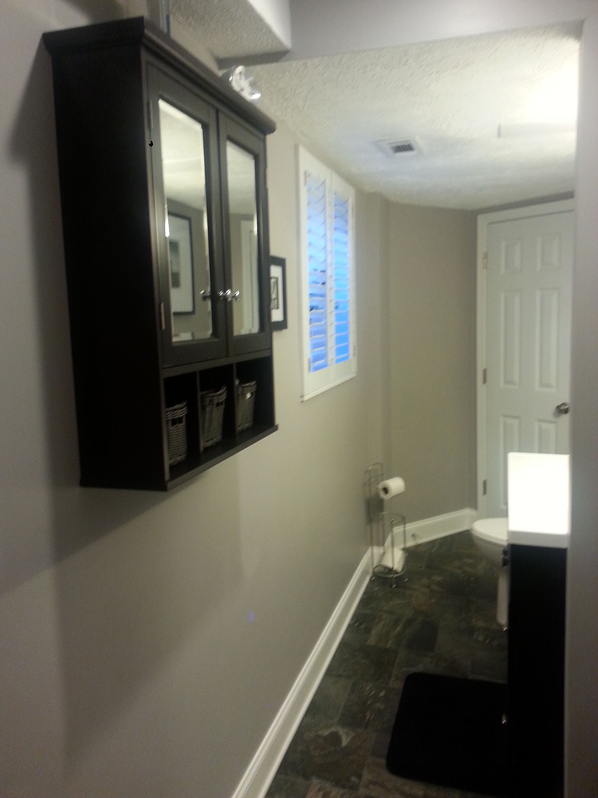 A bathroom with a toilet and a mirror on the wall