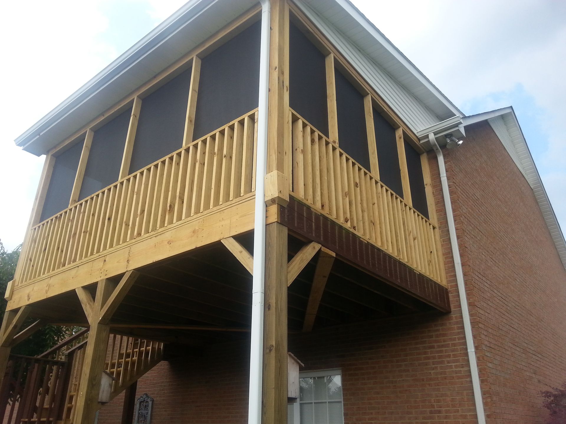 A screened in porch on the side of a brick house