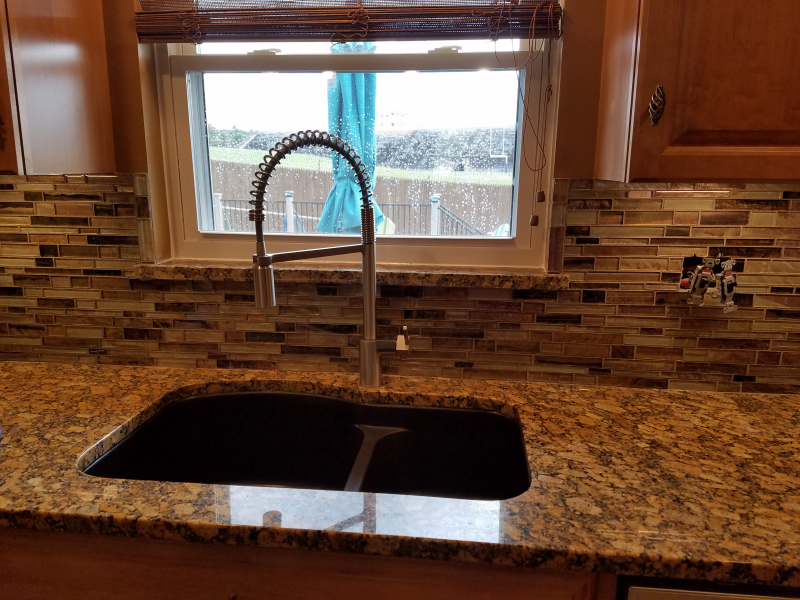 A kitchen sink with a faucet and a window in the background.