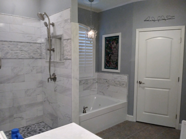 A bathroom with a tub , shower and mirror