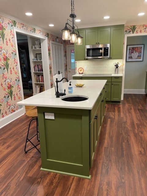A kitchen with green cabinets and a large island