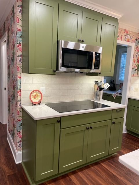 A kitchen with green cabinets and stainless steel appliances