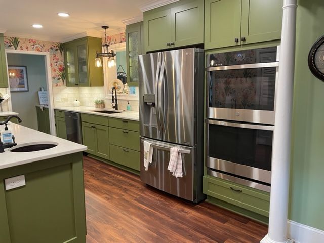A kitchen with green cabinets and stainless steel appliances.