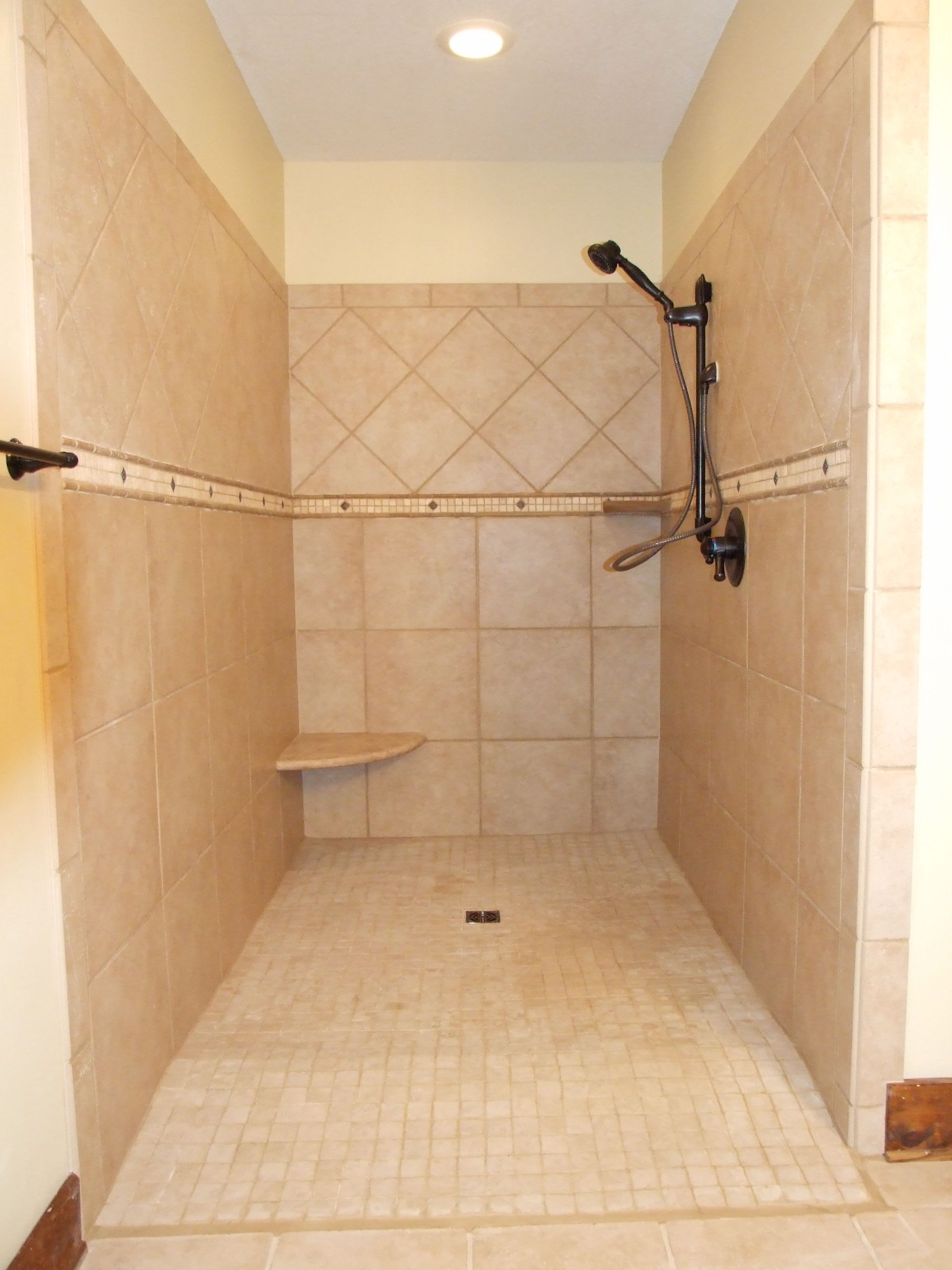 A walk in shower with a bench and a shower head