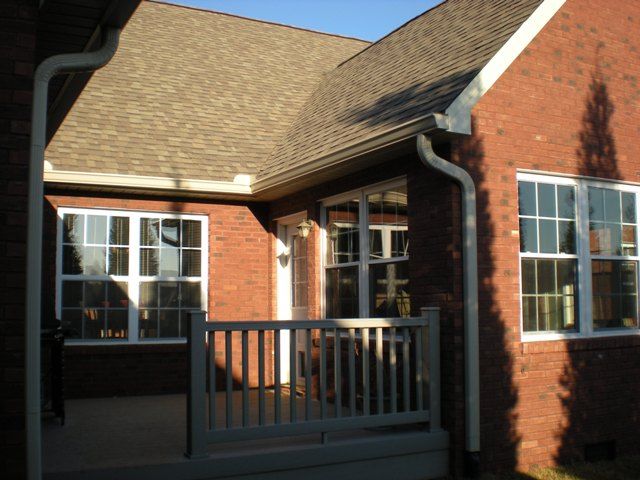 A brick house with a white railing and many windows