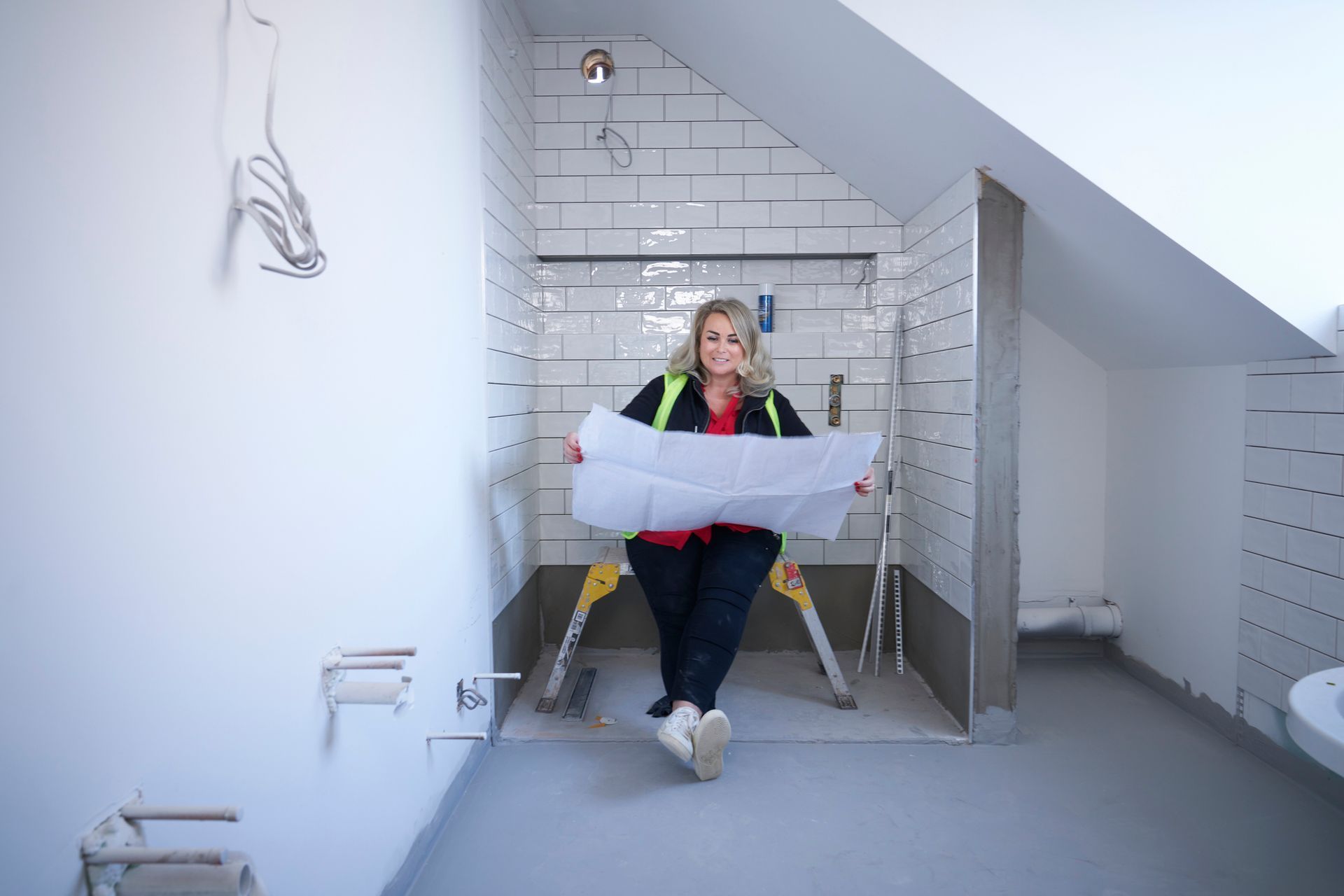 A woman is looking at the blueprints for a bathroom remodel.