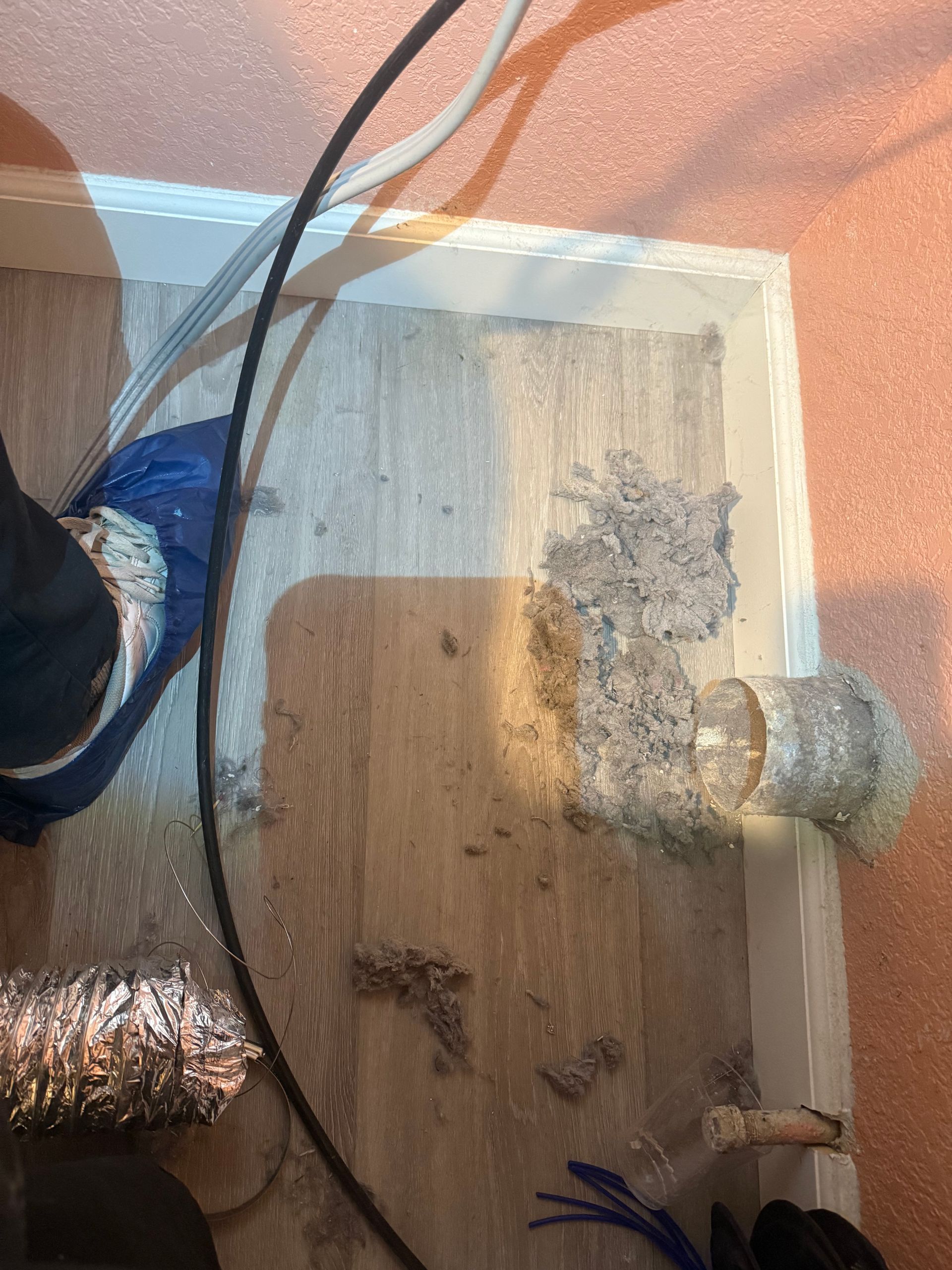 Wood floor with debris, ductwork, and a person's leg.