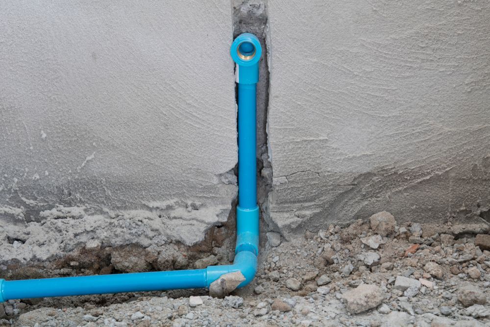 A Blue Pvc Pipe is Being Installed in a Hole in a Wall — Subat Plumbing Services in Kurri Kurri, NSW