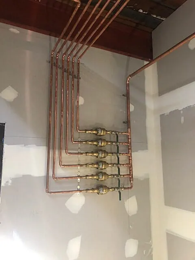 A Row of Copper Pipes Hanging From the Ceiling in a Room — Subat Plumbing Services in Kurri Kurri, NSW