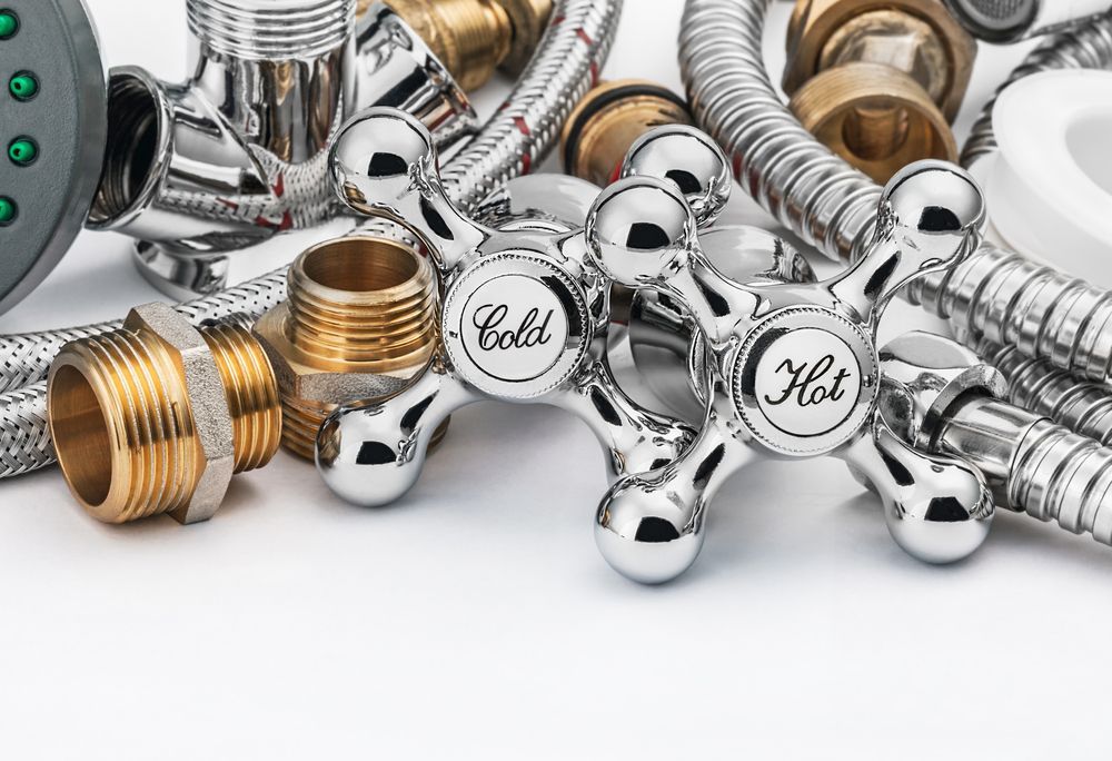 There are many different types of plumbing parts on a white background — Subat Plumbing Services in Cessnock, NSW