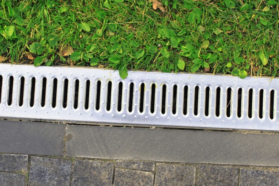 A Metal Drain on the Side of a Road Next to a Grassy Area — Subat Plumbing Services in Cessnock, NSW