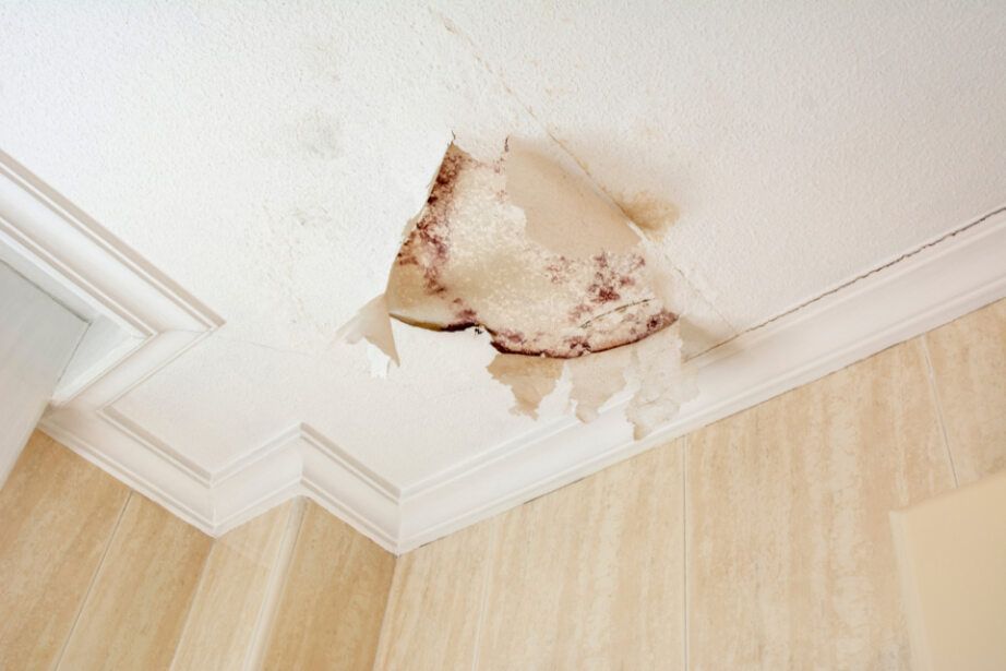 A Ceiling With a Hole in It and Water Coming Out of It — Subat Plumbing Services in Kurri Kurri, NSW