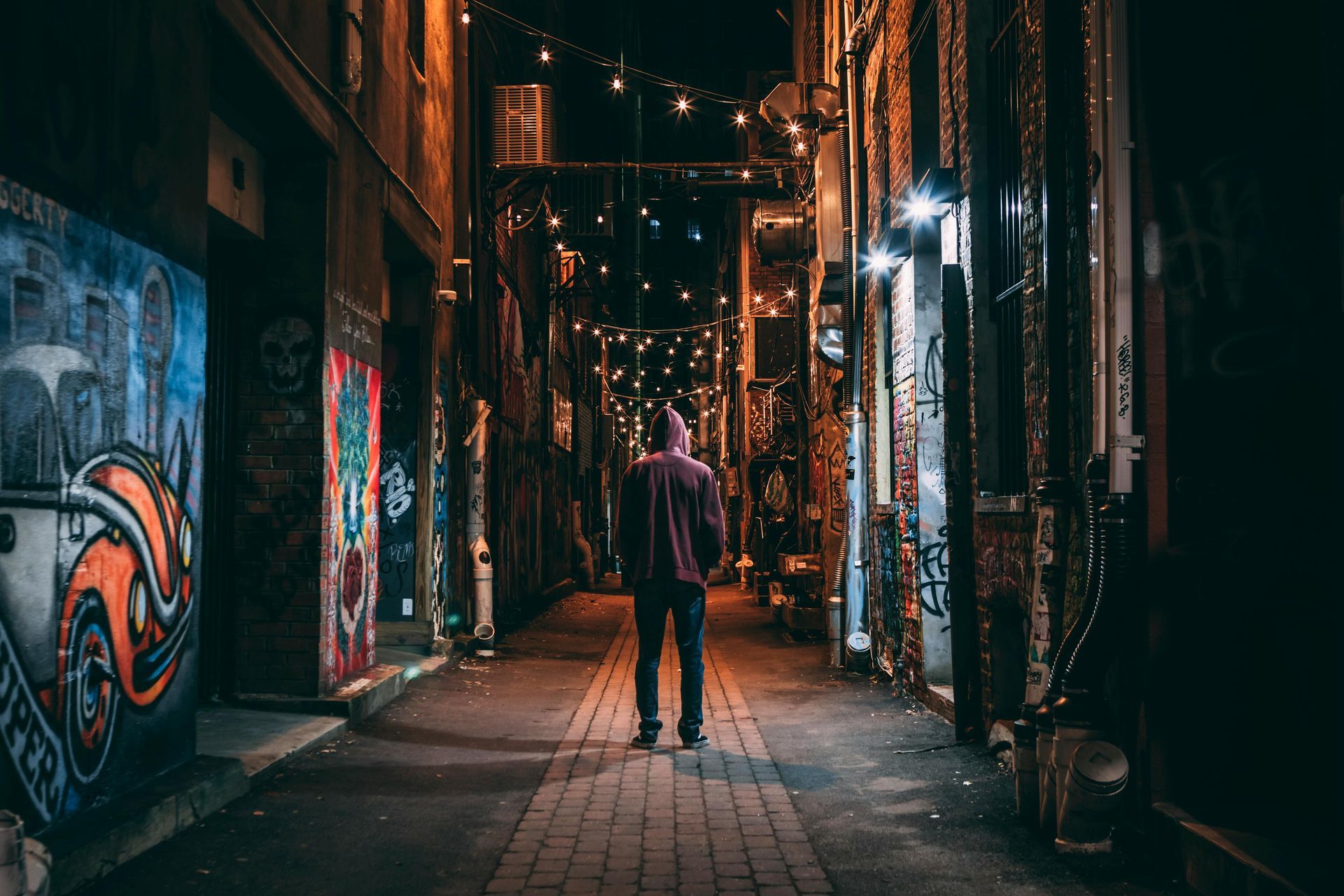 A youth is walking down a dark alleyway at night location global youth services