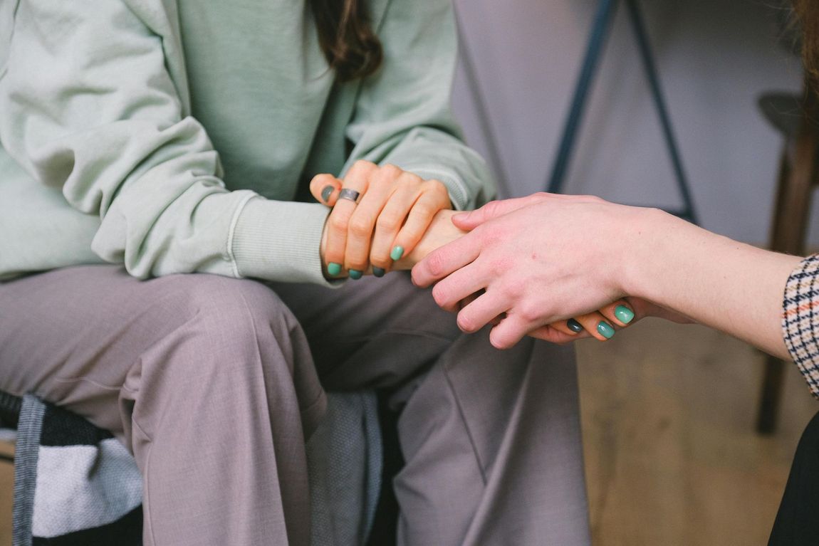 A woman is holding another woman 's hand while sitting down.