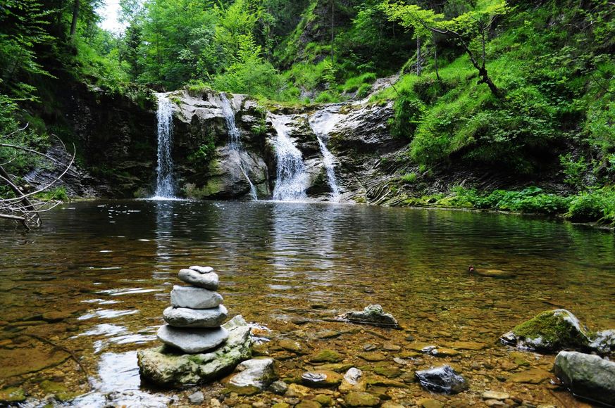 There is a waterfall in the background and a pile of rocks in the foreground.