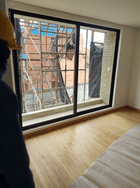 Persona dentro de una habitación mirando a través de una ventana de vidrio corrediza un andamio de construcción.