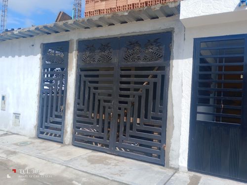 Puerta de metal negro y puerta lateral en un edificio de estuco blanco.
