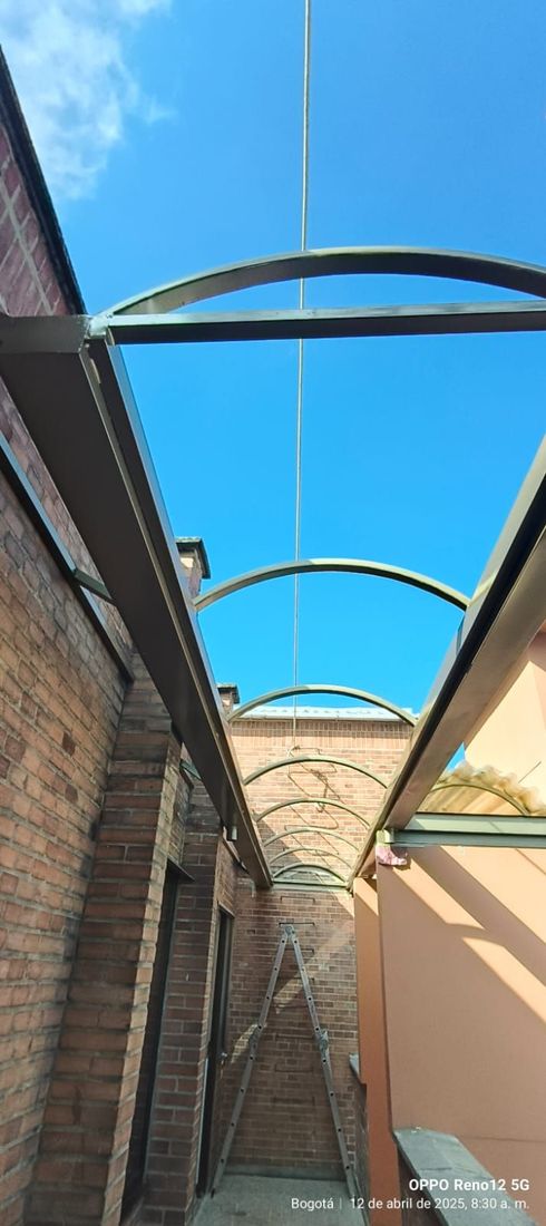 Mirando hacia arriba a la estructura de metal arqueada y al cielo azul entre edificios de ladrillo.
