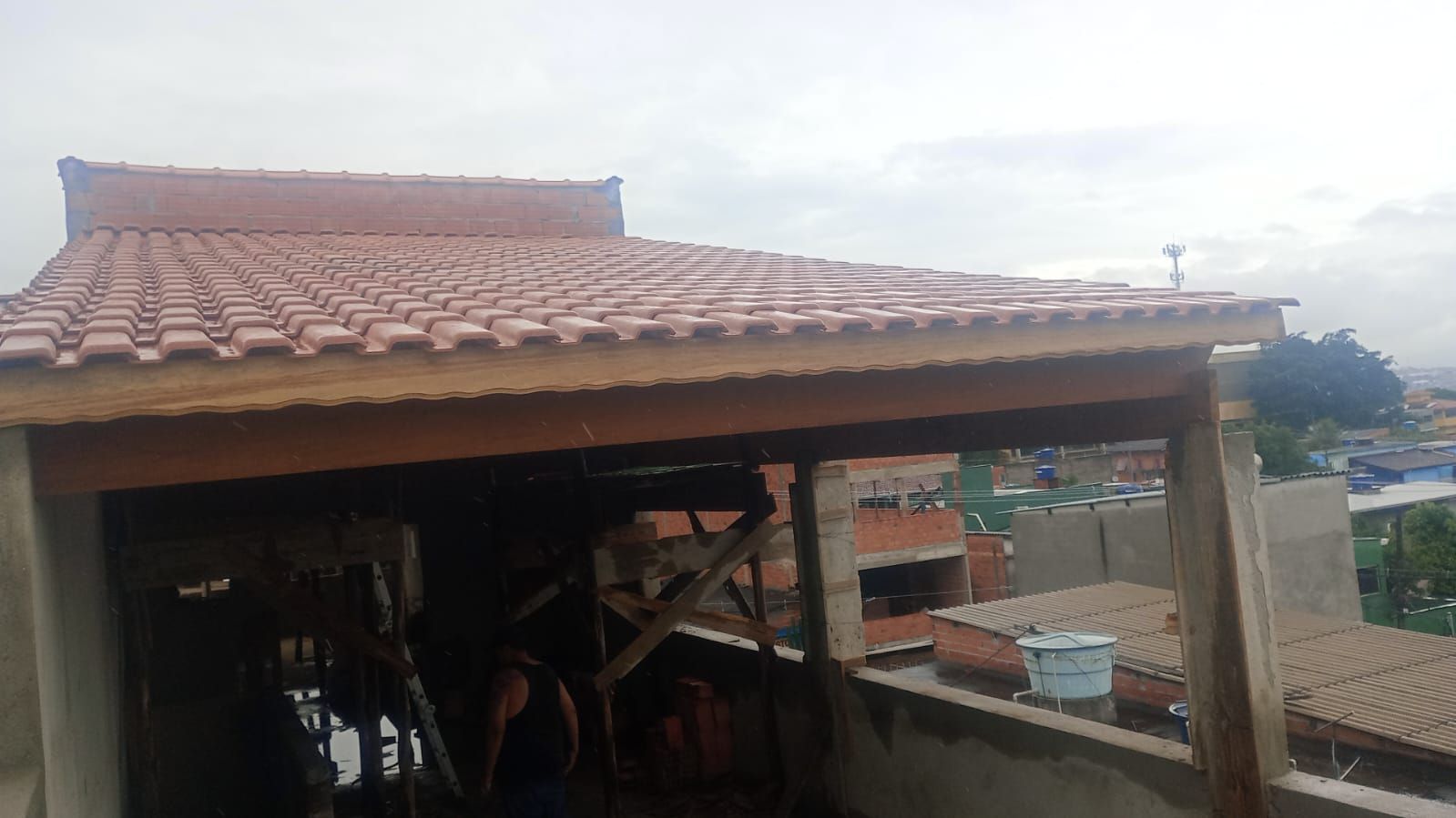 Telhado com telhas vermelhas e vigas de sustentação de madeira; céu nublado.